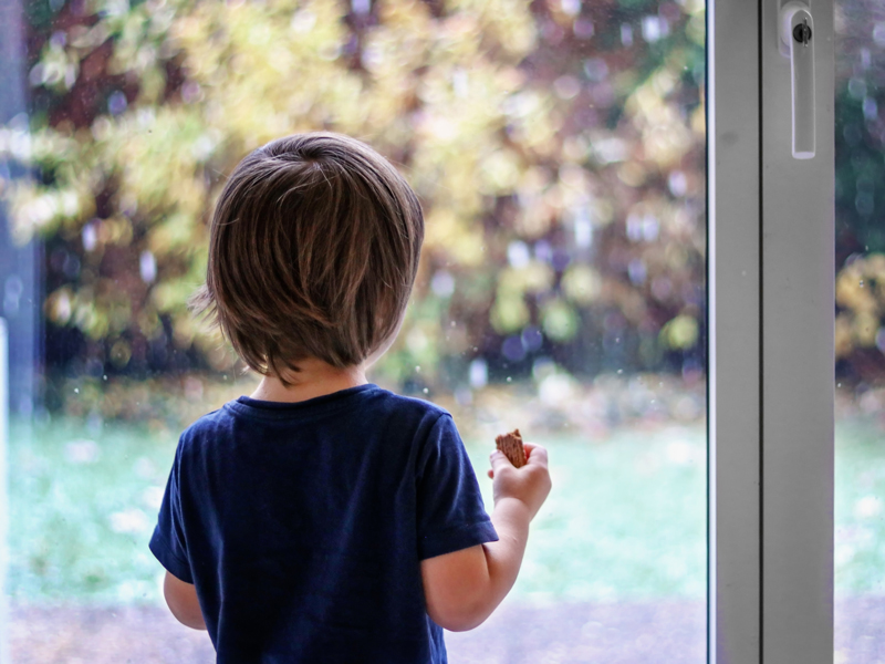 Lille dreng kigger ud af vinduet på det kolde vejr